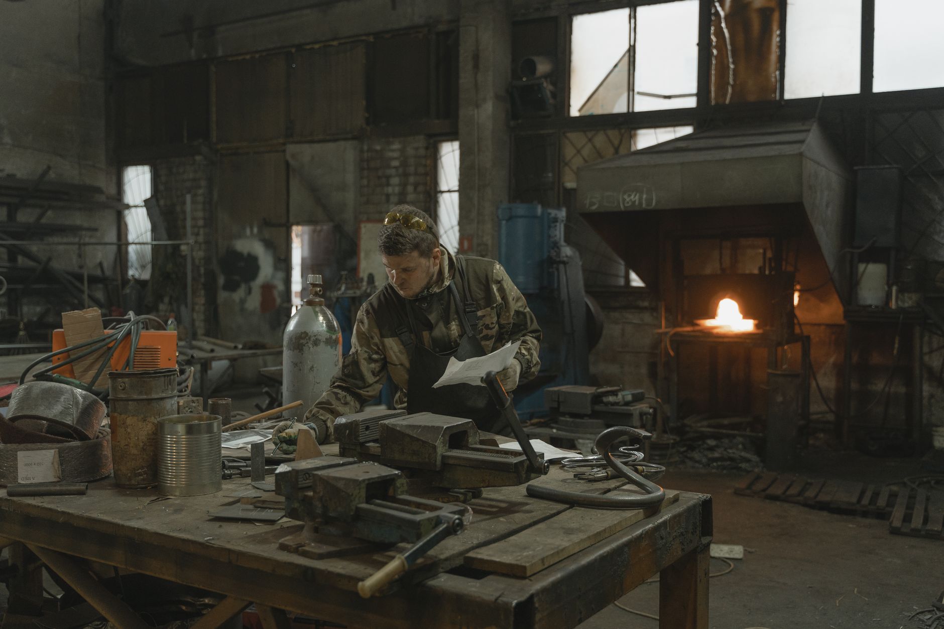 An experienced blacksmith working meticulously in a bustling forge, surrounded by tools and glowing metal.